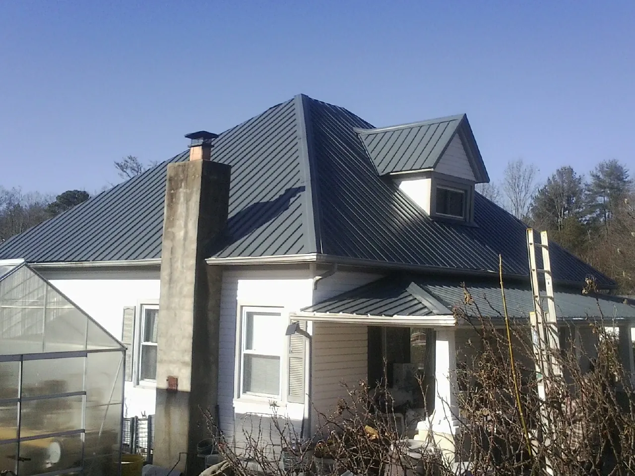 Dark blue standing seam metal roof on a white farmhouse with dormer — Slate & Tile Roof Repair by Roofing Brothers in Charleston Afb