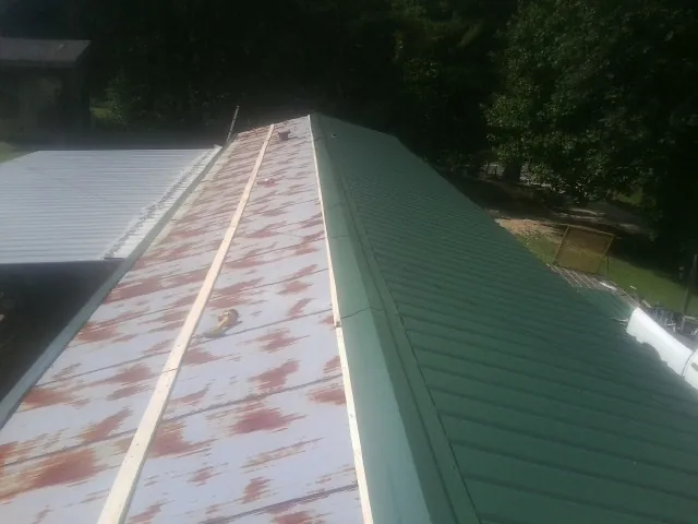 Old rusted panels beside newly installed green metal roofing — Wind Damage Roof Repair by Roofing Brothers in Charleston Afb