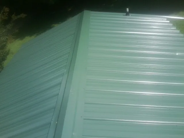 New green metal panels meeting at the ridge of a roof — Flat Roof Repair work by our crew in Charleston Afb