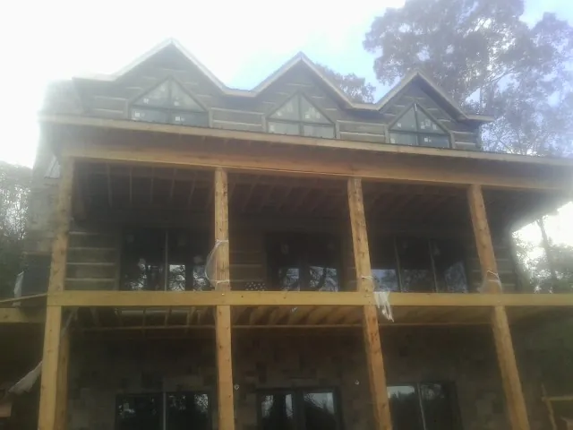 Dormers and porch framing on a large log home under construction — Roof Coating work by our crew in Charleston Afb
