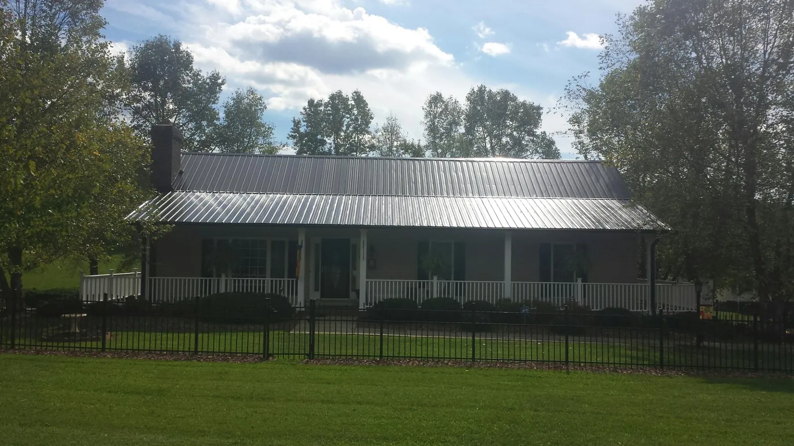 Gray metal roof on a brick ranch with a full width front porch — Gutter Guard Installation work by our crew in Charleston Afb