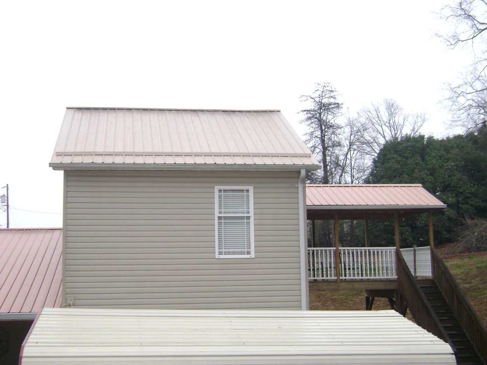 Tan metal roofs on a two story addition and attached porch, from a Roof Replacement job in Charleston Afb