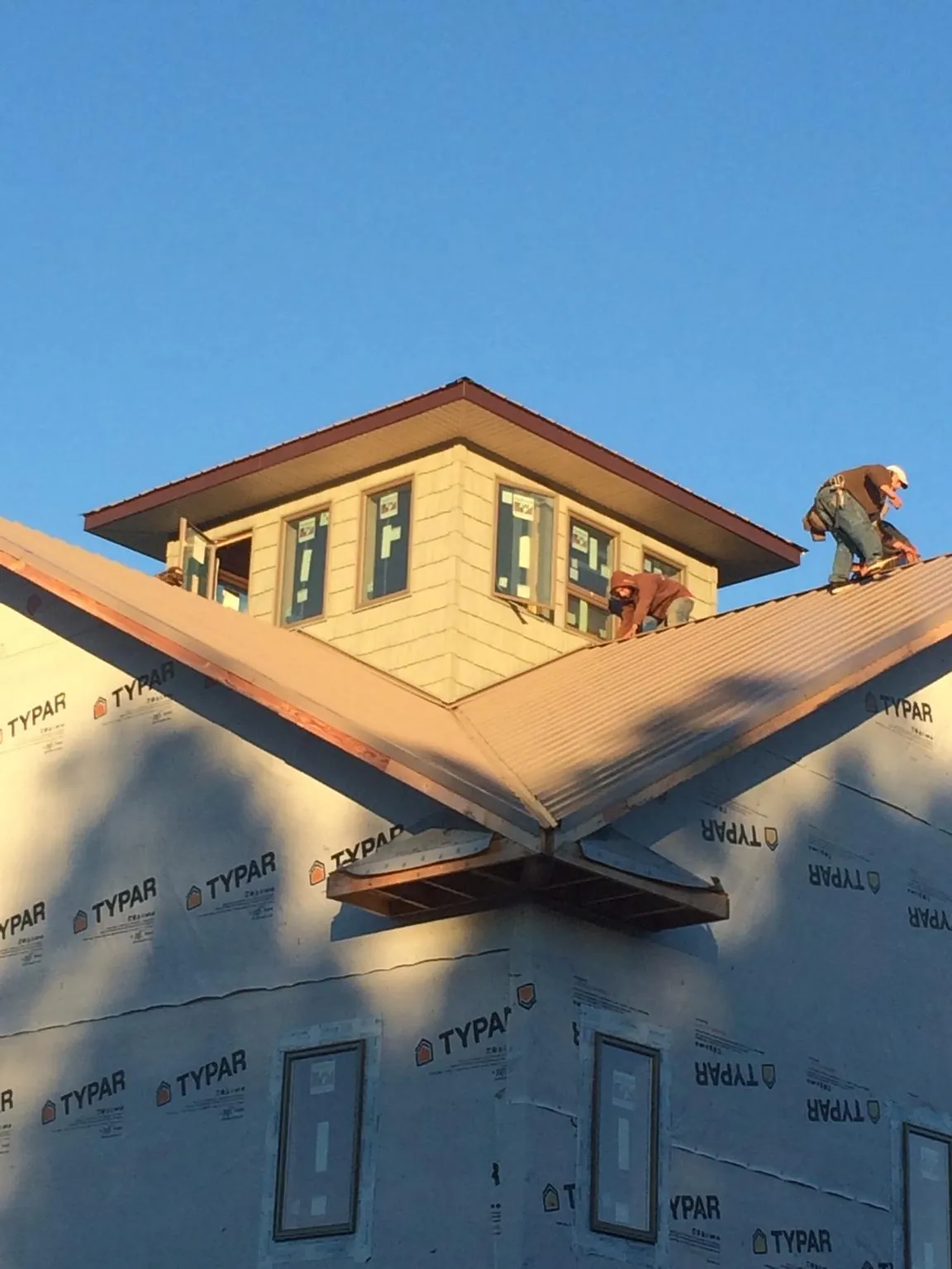 Roofers working around a rooftop cupola on a new metal roof at sunset — Roof Waterproofing in Charleston Afb by Roofing Brothers